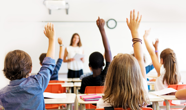 Children with raised hands in classroom