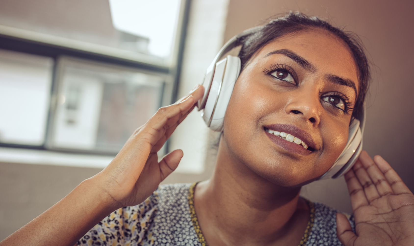 Woman listening to audiobook with headphones on - Canva