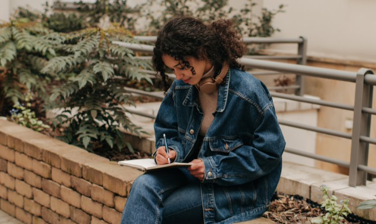 Young woman writing in notebook - sourced from Canva