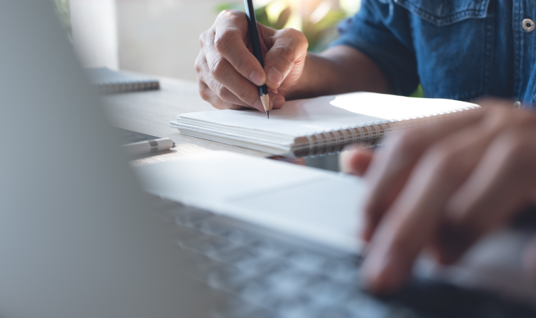 Person using computer and taking notes