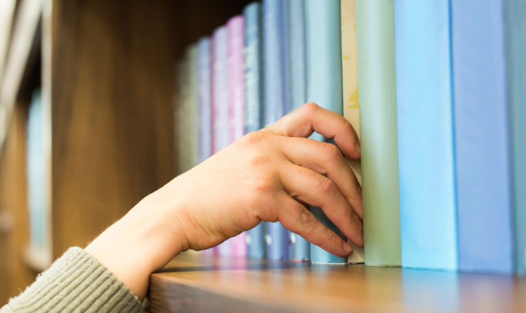 Hand reaching to pull a book off a shelf