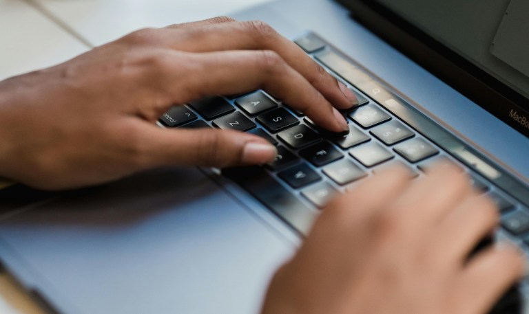 Hands type on laptop keyboard